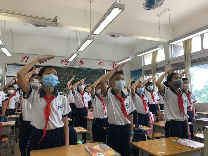 南武实验小学升旗仪式，同学们面向教室内的国旗行注目礼，唱国歌。.jpg